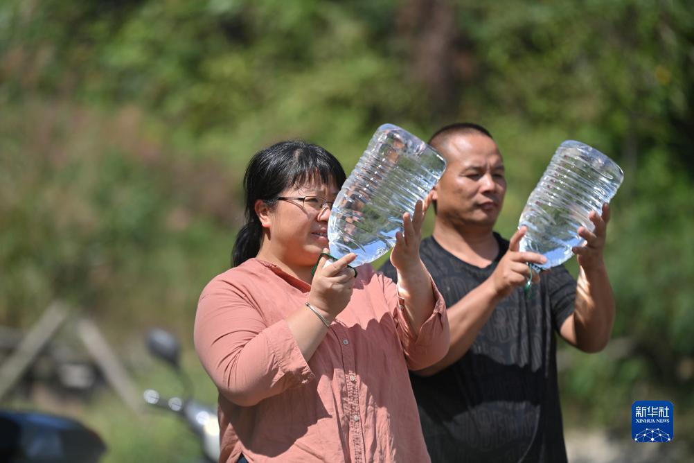 楊寧（左）在查看村民剛剛采集的水樣，為山泉水引水工程做準(zhǔn)備（10月8日攝）。新華社記者 黃孝邦 攝